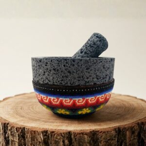 Molcajete de piedra volcánica con base decorada en arte huichol de chaquira sobre un tronco de madera