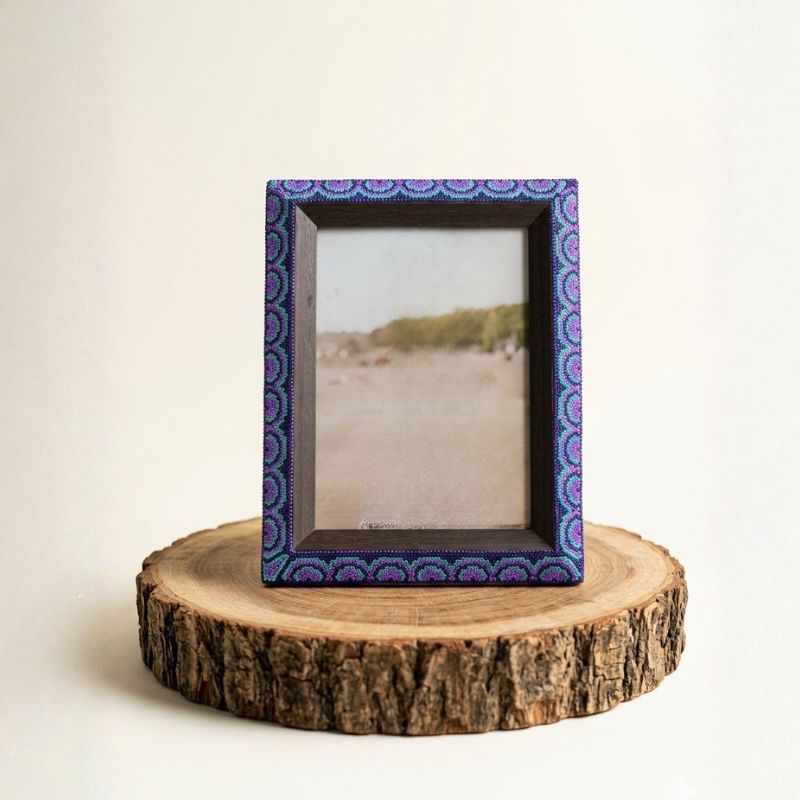 Marco de fotos artesanal con arte wixárika de flores violetas en chaquira, ideal para decoración mexicana de lujo.